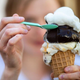 Person eating an ice cream cone with a spoon